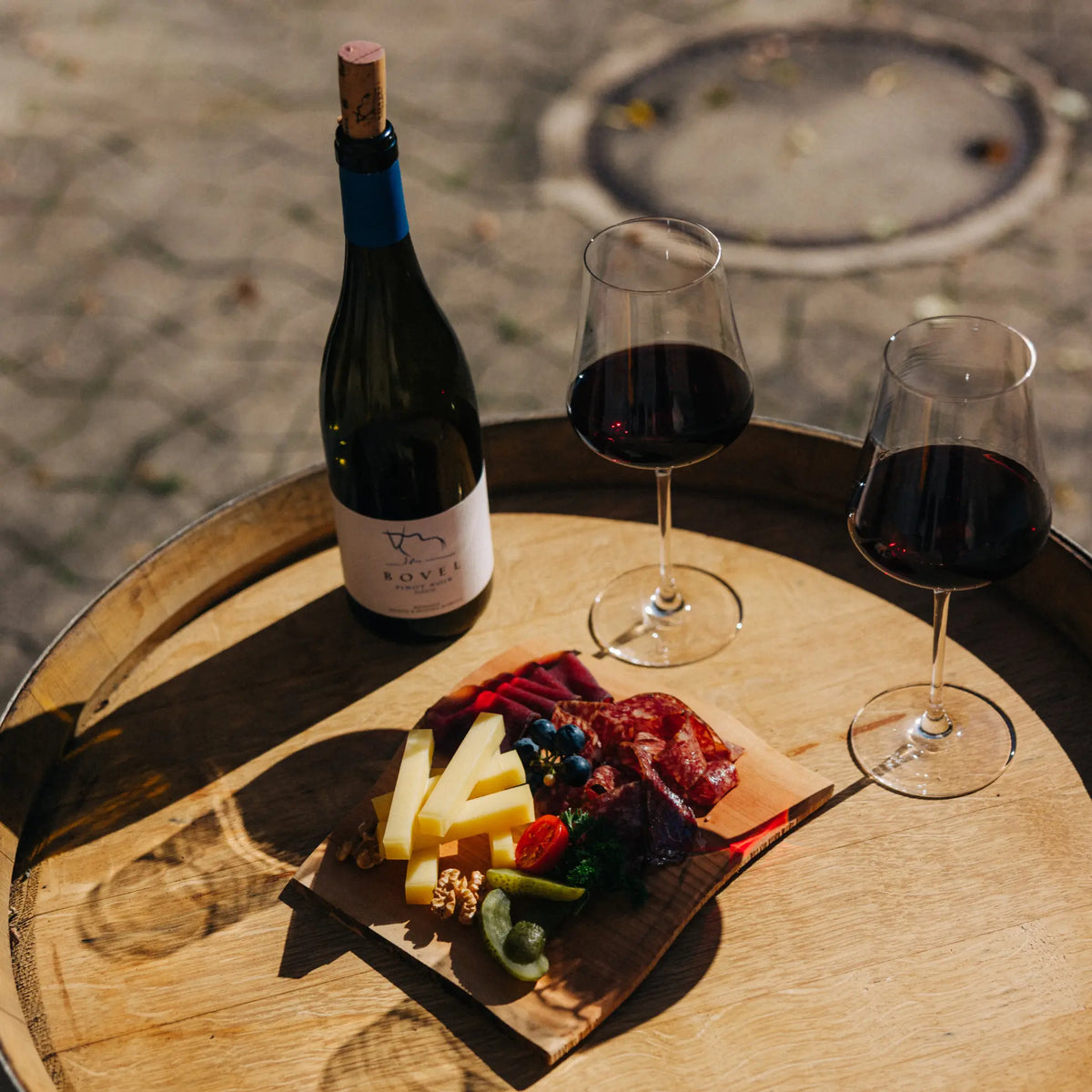 Bovel Pinot Noir vom Weingut Marugg mit Käse und Charcuterie auf einem Holzfass in Fläsch.