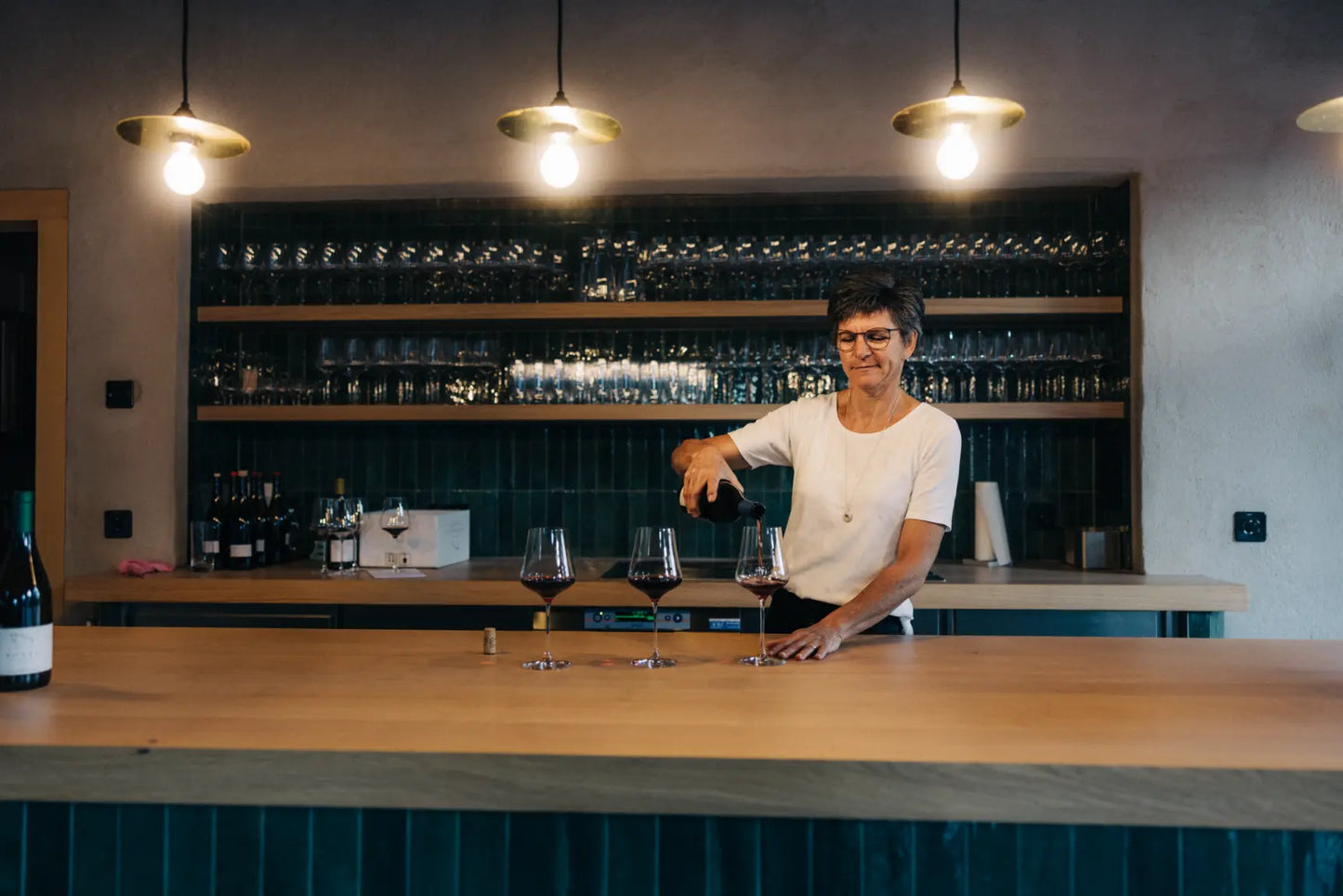 Monika Marugg schenkt Rotwein an der Bar des Weinguts in vorbereitete Weingläser ein.