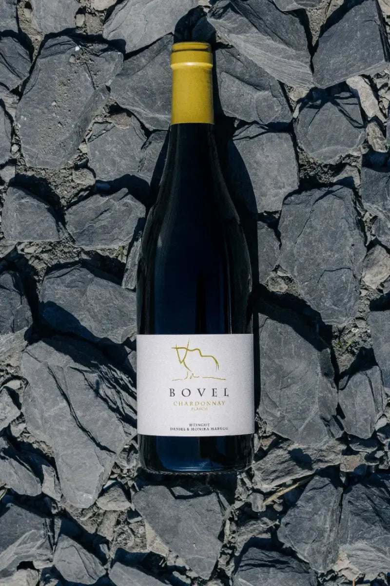 Flasche Weisswein „Bovel Chardonnay“ des Weinguts Marugg auf steinigem Untergrund.